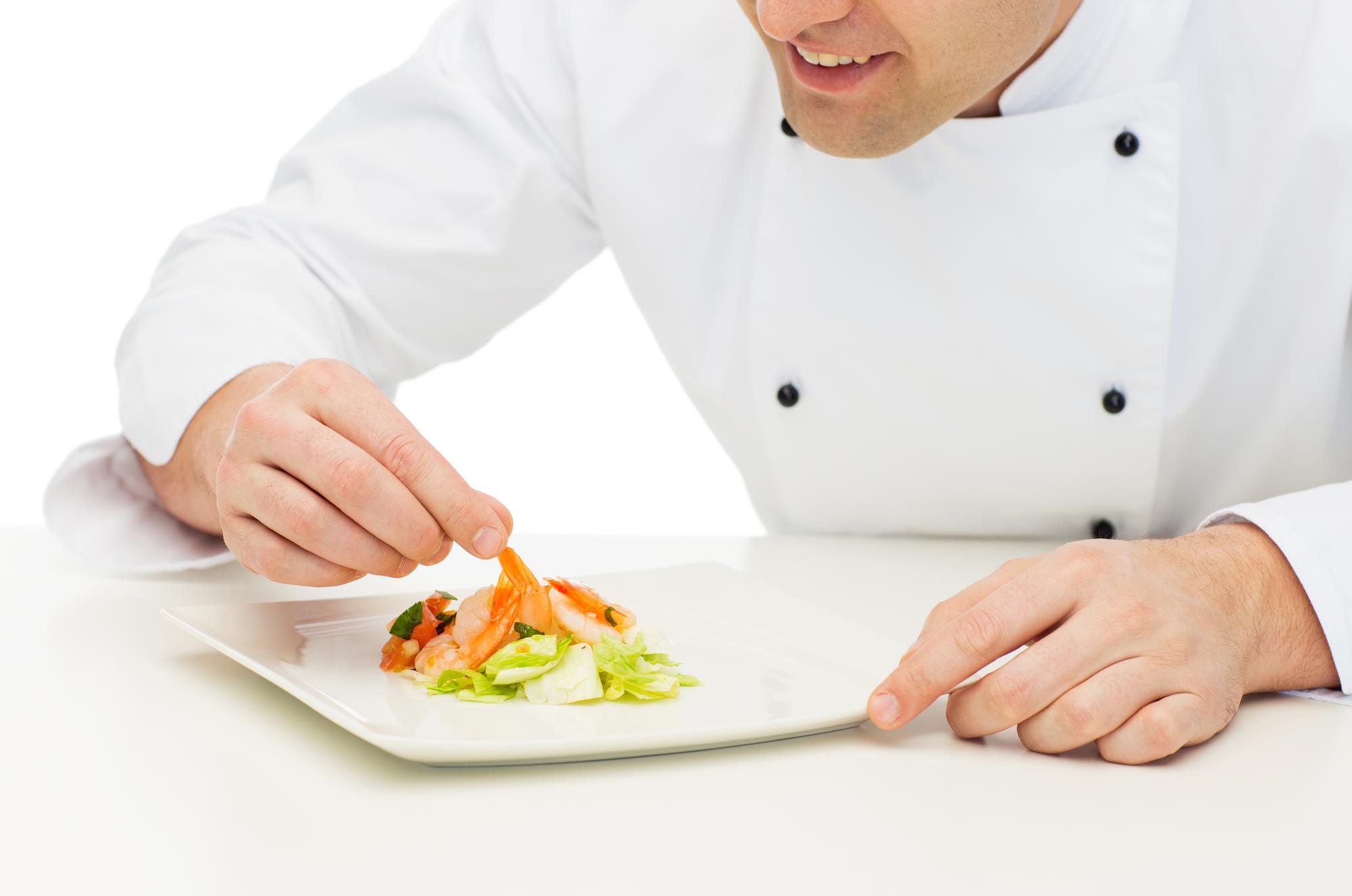 Student plating a dish under instructor guidance