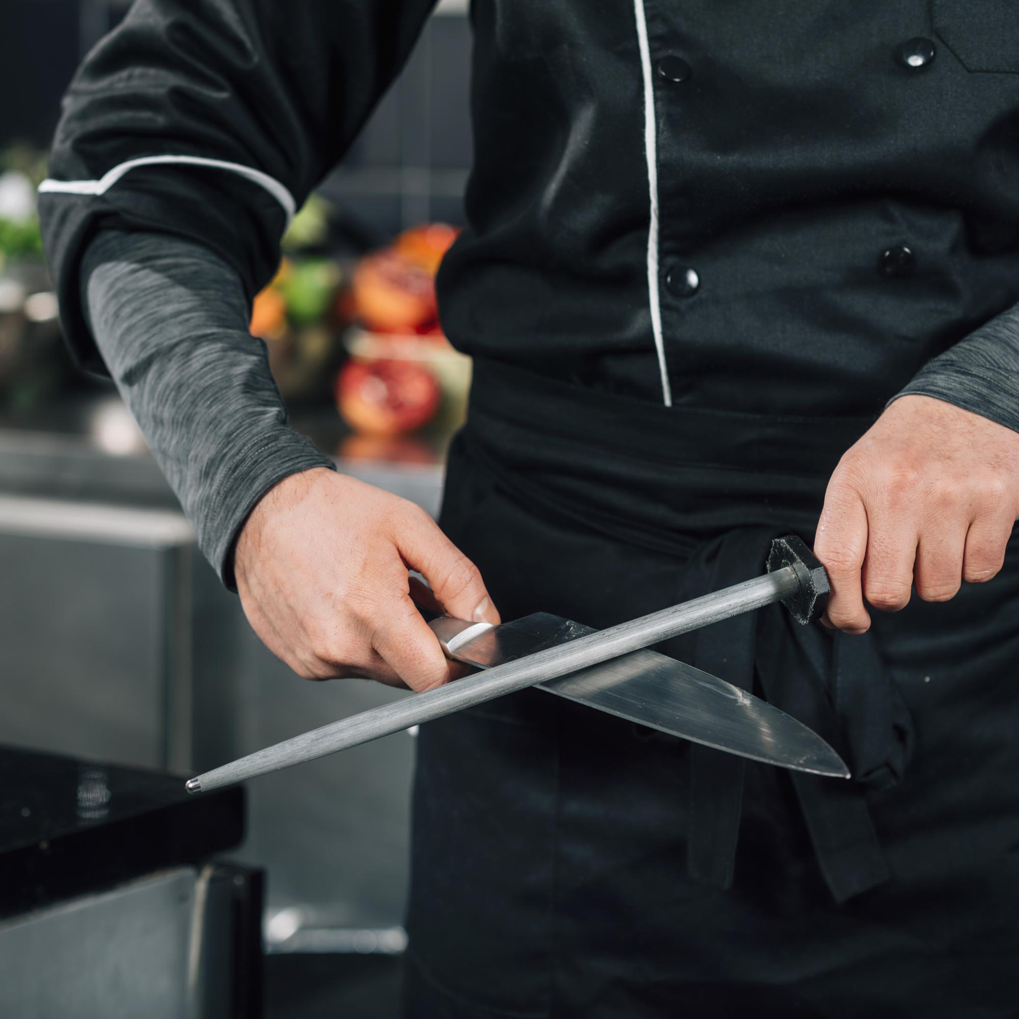 Instructor demonstrating knife technique in modern kitchen